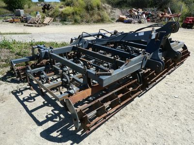a close up of a tractor plow sitting on a dirt field