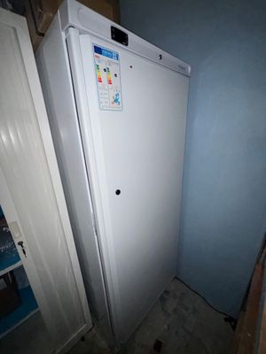 a white refrigerator in the corner of a room next to a door