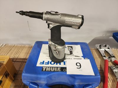 une perceuse posée sur une boîte bleue, avec des outils sur la table