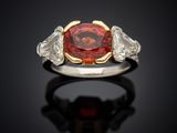 a red diamond and diamond ring with two white diamonds on a black surface
