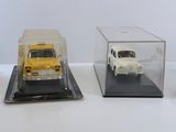 trois modèles réduits de voitures sont exposés dans une vitrine posée sur une surface blanche