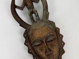 une image représentant un masque en bois sur lequel est assis un homme