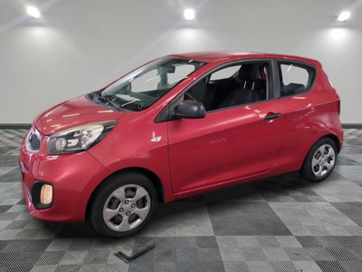 une voiture rouge est garée dans une pièce au sol en damier
