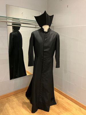 un mannequin vêtu d'une robe noire dans une pièce avec un miroir