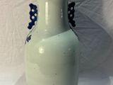a white vase with blue flowers on it on a white surface