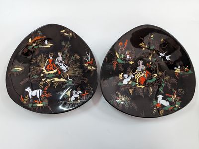 pair of black and gold plates with asian scenes on them