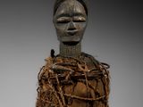 un gros plan sur une sculpture représentant une personne dont la tête repose sur un morceau de bois