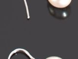 une paire de boucles d'oreilles en perles blanches posées sur un fond noir
