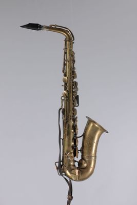 un gros plan d'un saxophone posé sur un pupitre, sur fond blanc