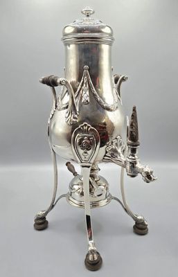 an antique silver plated coffee urn with a bird on it