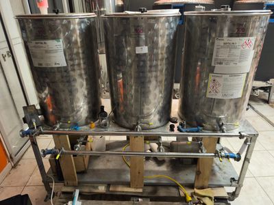 trois grandes cuves en acier inoxydable posées sur un chariot