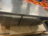 stainless steel counter top in a commercial kitchen with a conveyor belt in the background