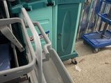 a blue cart with a yellow handle next to a green bin