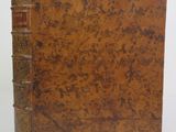 an old book with a brown cover sitting on top of a white table