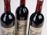 three bottles of red wine sitting next to each other on a white surface