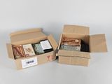 two boxes of assorted items sitting on top of a white surface