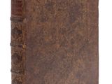 un vieux livre à la couverture brune posé sur une surface blanche