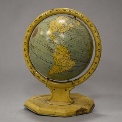 an old yellow and green globe on a wooden stand on a gray background