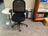 a black office chair with a black seat in the corner of a room