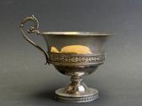 une coupe ancienne en argent avec une anse, sur fond noir