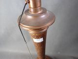a copper lamp on a wooden stand with a cord