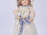 porcelain doll of a little girl in a white dress and hat