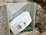 a white box with wires attached to it near a rock