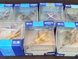 Six boîtes contenant un assortiment d'avions miniatures sont posées sur une table.