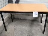 une table en bois sur laquelle est posée une pancarte, devant un immeuble