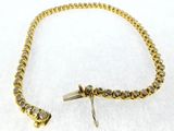 a close up of a gold bracelet with diamonds on a white surface