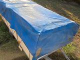 a blue cover on a trailer that is parked in the grass