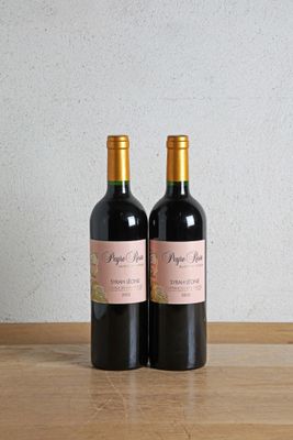 two bottles of wine sitting on a wooden table next to each other