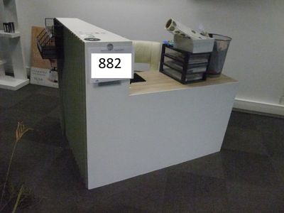 Une borne d’accueil mélaminé blanc asymétrique, façade rayée…