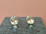 une paire de boucles d'oreilles à clous plaquées or, posées sur un socle en marbre