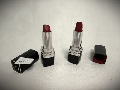 two red lipsticks sitting next to each other on a white surface