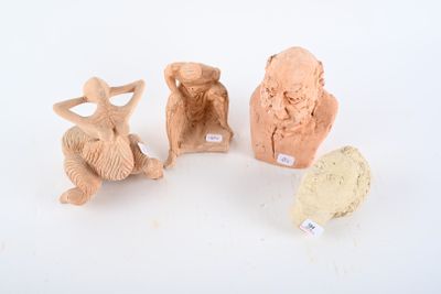 three clay figurines of different shapes and sizes on a white surface