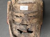 a wooden mask that has a tag on it