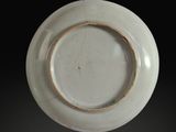 a white plate with a brown rim on a black background