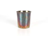 une tasse en métal posée sur une surface blanche