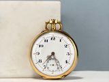 a gold pocket watch sitting on a marble block
