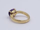 a close up of a gold ring with a purple stone