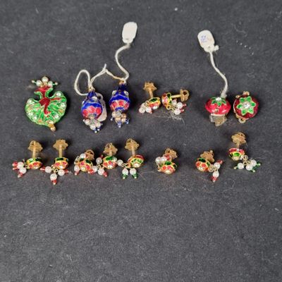 Six paires de décorations de Noël sont disposées sur une surface noire.