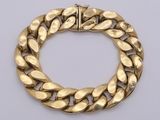 a gold bracelet with a curb link on a white background