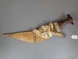 un couteau en bois avec un manche marron posé sur une surface grise