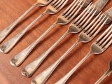 six forks and a knife on a wooden table