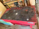 a red table with a black top sitting in a garage