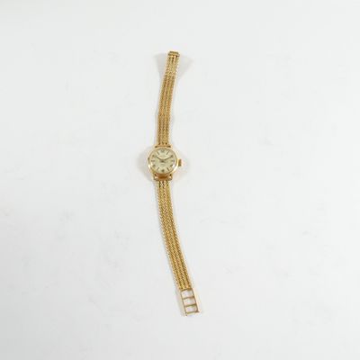 une montre en or avec une chaîne autour du poignet