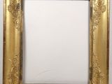 a gold framed mirror with ornate design on a white wall