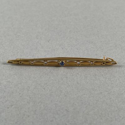 a close up of a gold bar with a blue stone on it