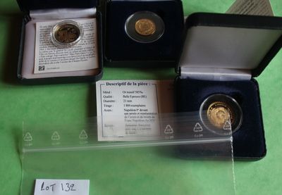 three gold coins are in a case on a green surface